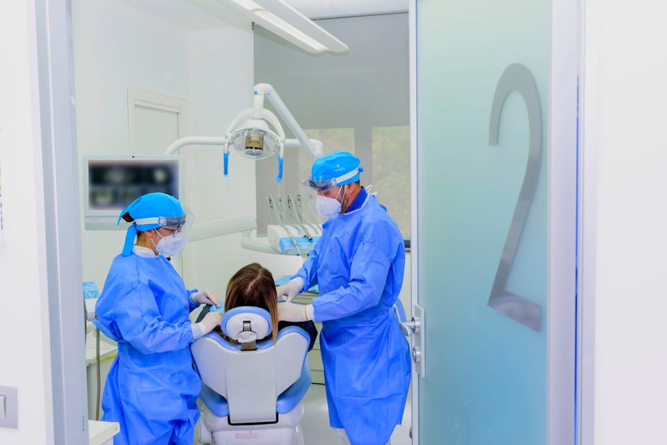Due operatori dello studio al lavoro; sullo schermo, le immagini di una TAC